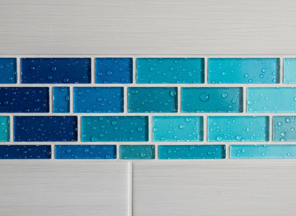 Detailaufnahme eines Glasmosaiks in Blautönen als Akzent in einer Duschnische